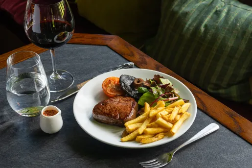 Plate of food with a fork and knife on either side, and a wine glass