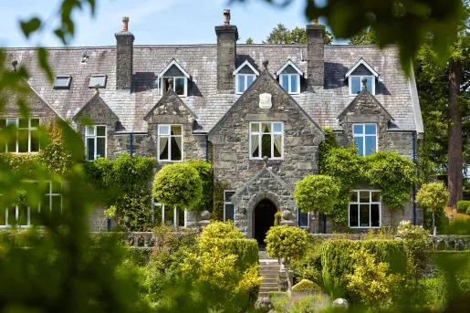 Exterior view of grey, stone building with large bushes in front