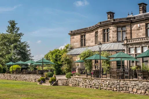 Exterior view of stone building with an outdoor patio with green umbrellas