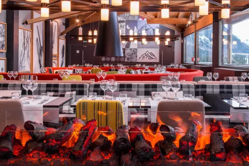 Restaurant dining hall with long tables and cushioned chairs, with light fixtures from the ceilings