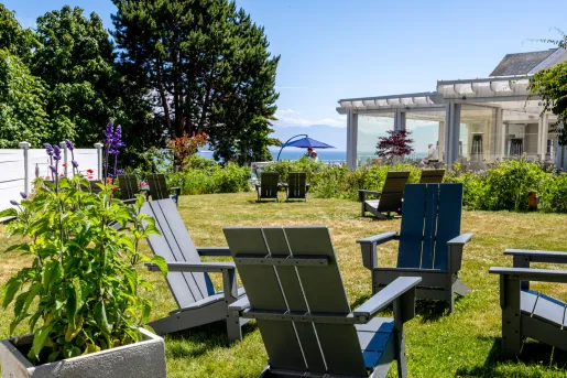 Exterior view of the historic Sooke Harbour House hotel in the Gulf Islands, Canada, featuring its wooden architecture, garden lawn, and surrounding furniture.