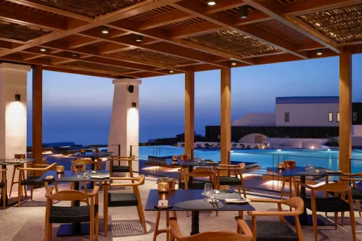 Open air restaraunt with a pool and the ocean in the background.