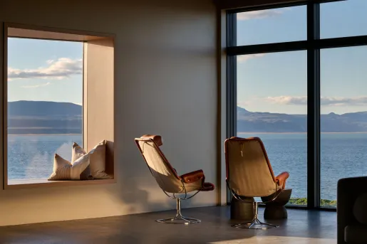 Two mid-century modern leather and canvas lounge chairs overlooking a scenic view of the water at the Black Sand Hotel in  Ölfus, Iceland.
