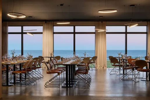 ÓMUR restaurant inside the Black Sand Hotel in the Ölfus region in South Iceland  features an open-plan, minimalist dining space with floor-to-ceiling panoramic windows.