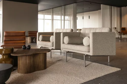 Mid-century style lounge seating featuring upholstered neutral fabric armchairs, leather chairs and organic shaped wood coffee tables at the Black Sand Hotel in Ölfus, Iceland.