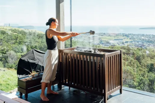 Woman pouring water into a stone sauna