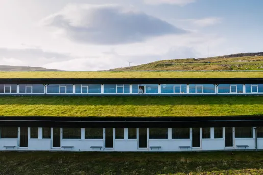 Exterior view of long hotel building with a grass roofing