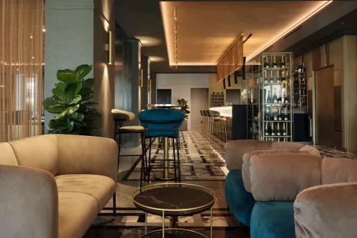 The Boutique Hotel Stresa lobby lounge with a modern, deep blue and green velvet seating, polished brass accents, and mirrored surfaces.