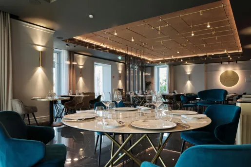 The restaurant at the Boutique Hotel Stresa in Stresa, Italy, featuring modern lighting, dark flooring, and bright blue armchairs.