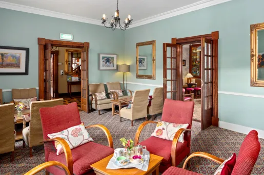 Seating and lounge area with red and beige, cushioned chairs surrounding coffee tables