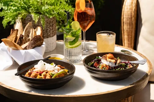Circular, white dining table with two bowls of food and two glasses of drinks