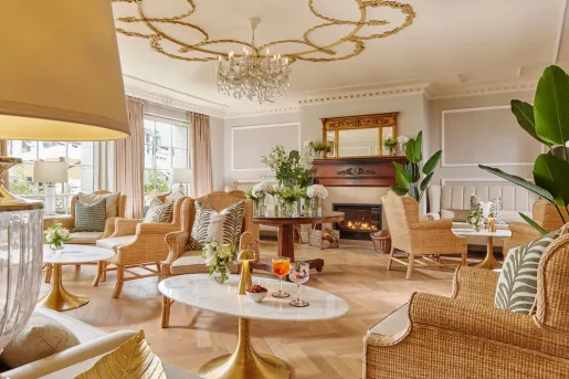 Lounge area in front of a fireplace, with circular tables and woven chairs