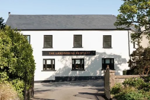Exterior view of white and gray building with trimmed bushes in front