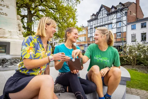 Three women sitting on a ledge, reaching into a box of chocolates