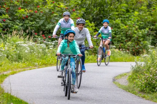 Family biking on an empty road, with a forest in the background