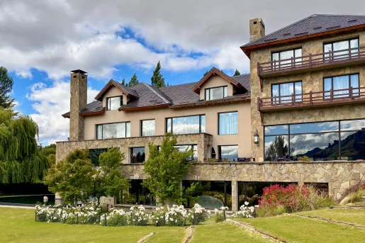 Exterior view of gray hotel building with large windows and a grass field in front