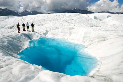 Hikers standing on a glacier in Alaska.