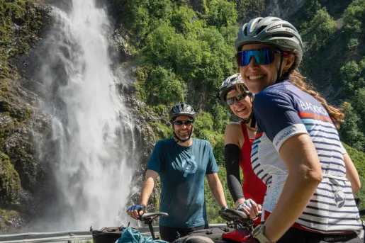 A group of cyclists pose near a waterfall.