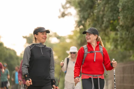 Group of women, using hiking poles and walking through a trail