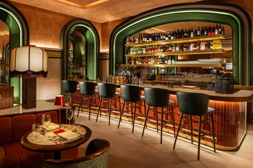 Bar and lounge with green arch doorways and green stools in front of a dimly lit bar counter