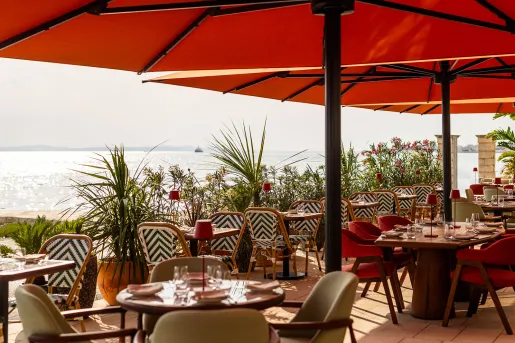 Outdoor patio with dining tables and large, red umbrellas