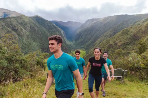 Group of people smiling while hiking up a grassy hill