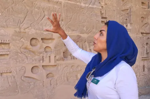 A guide explains the ancient wall carvings at Deir el-Medina in Luxor, Egypt.