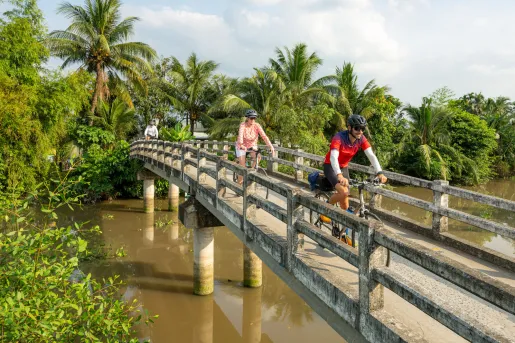 Group of people biking on a wooden bridge over a river