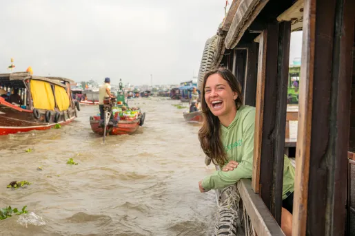 Woman smiling while poking her head out of a boat in a lake