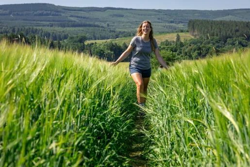 Woman walking through a tall field of weeds