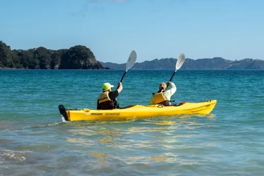 Yellow kayak with two people paddling in the middle of the ocean