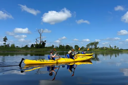 Two people paddling on a yellow kayak
