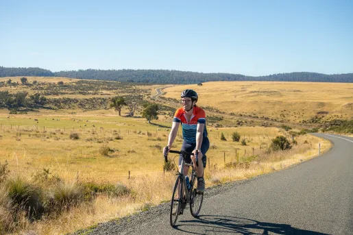 Man smiling while biking on an empty road in a valley