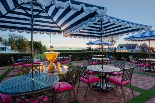 Outdoor patio with multiple circular tables and chairs, and striped white and black umbrellas