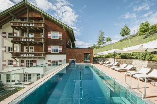 Exterior view of white and brown hotel building with an outdoor pool in front