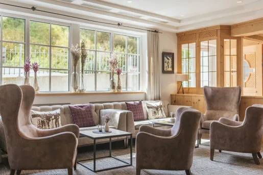Seating area and lounge with beige, cushioned chairs and large windows