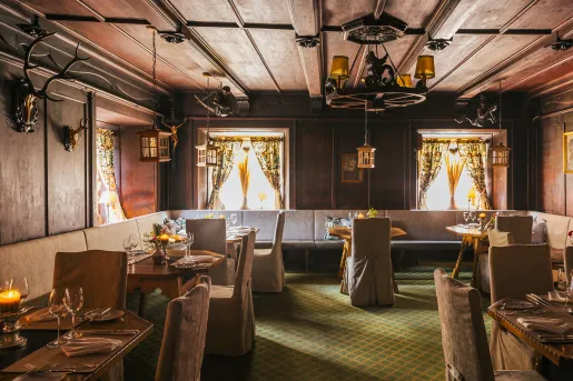 Dimly lit restaurant dining area with cushioned chairs and large dining tables