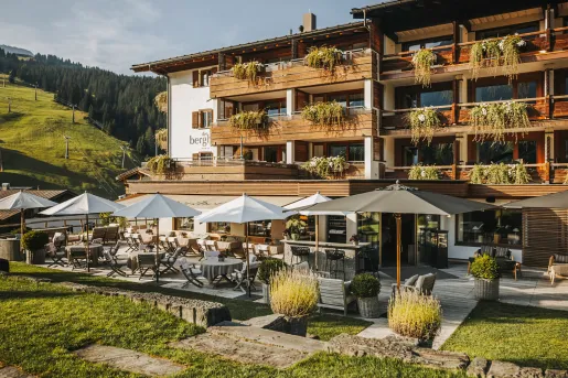 Exterior view of brown hotel building with balconies and a grass lawn in front