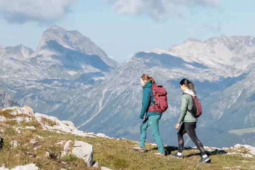 Two women walking on a trail at the top of a mountain