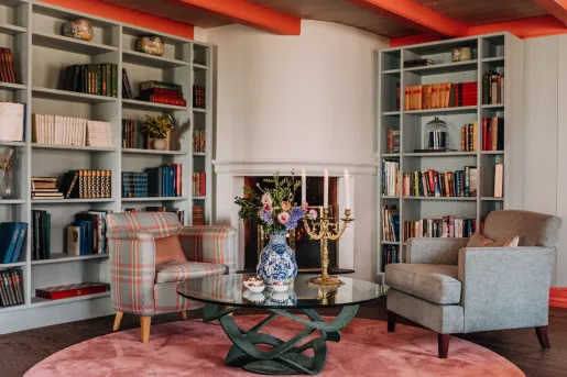 Library and lounge area with cushioned sofas in front of book shelves
