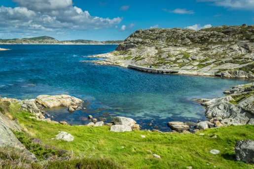 Coastal shore with a grassy hill and blue water