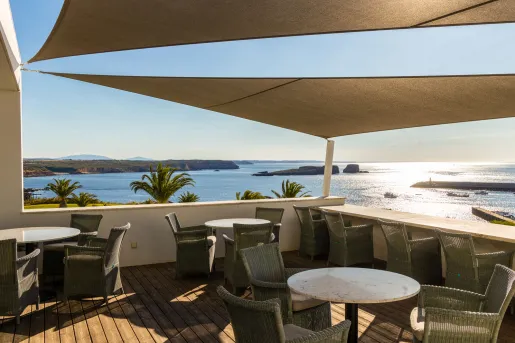 This terrace at the Memmo Baleeira Hotel in Sagres, Portugal, featuring comfortable outdoor seating, tables, and sun sails.