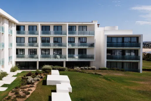 The exterior of the Memmo Baleeira Hotel in Sagres, Portugal, featuring white walls and glass-railed balconies.