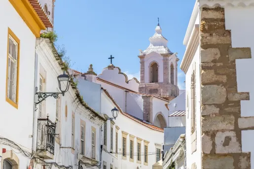 Historic street in the old town center of Lagos, Algarve, Portugal, looking toward the distinctive white bell tower of the Igreja de Santo António.