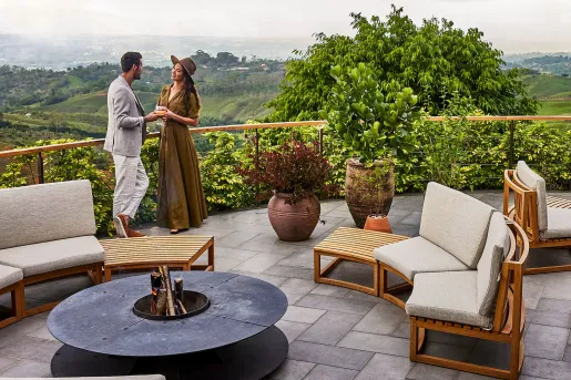 Man and woman standing on a rooftop balcony with cushioned chairs