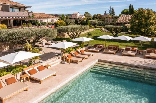 La Bastide Saint Georges hotel in Forcalquier features a tranquil outdoor pool surrounded by pool lounge chairs and olive trees.