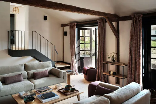 Living room area with gray sofas and a black staircase in the back