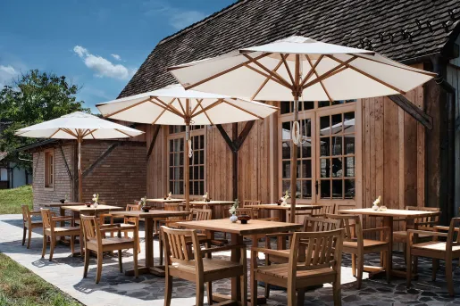 Outdoor patio and dining area, with wooden chairs and tables under white umbrellas