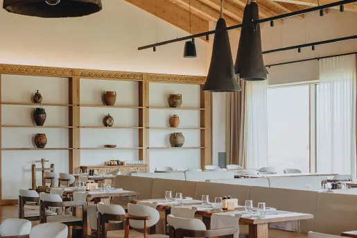 Restaurant dining area with white chairs and tables, with pottery along the walls