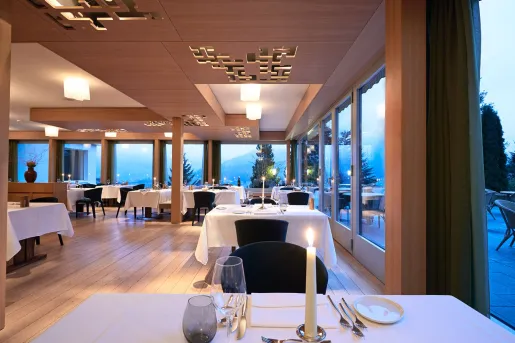 Restaurant dining area with white cloths and candles over square tables